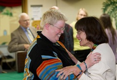 The Rev. Amy DeLong (left, foreground) is congratulated by supporter Rebecca Neal Niese (right) at the conclusion of her church trial at Peace United Methodist Church in Kaukauna, Wis. At left rear is Bishop Clay Foster Lee Jr.,  who served as presiding officer for the trial.  A UMNS photo by Mike DuBose.